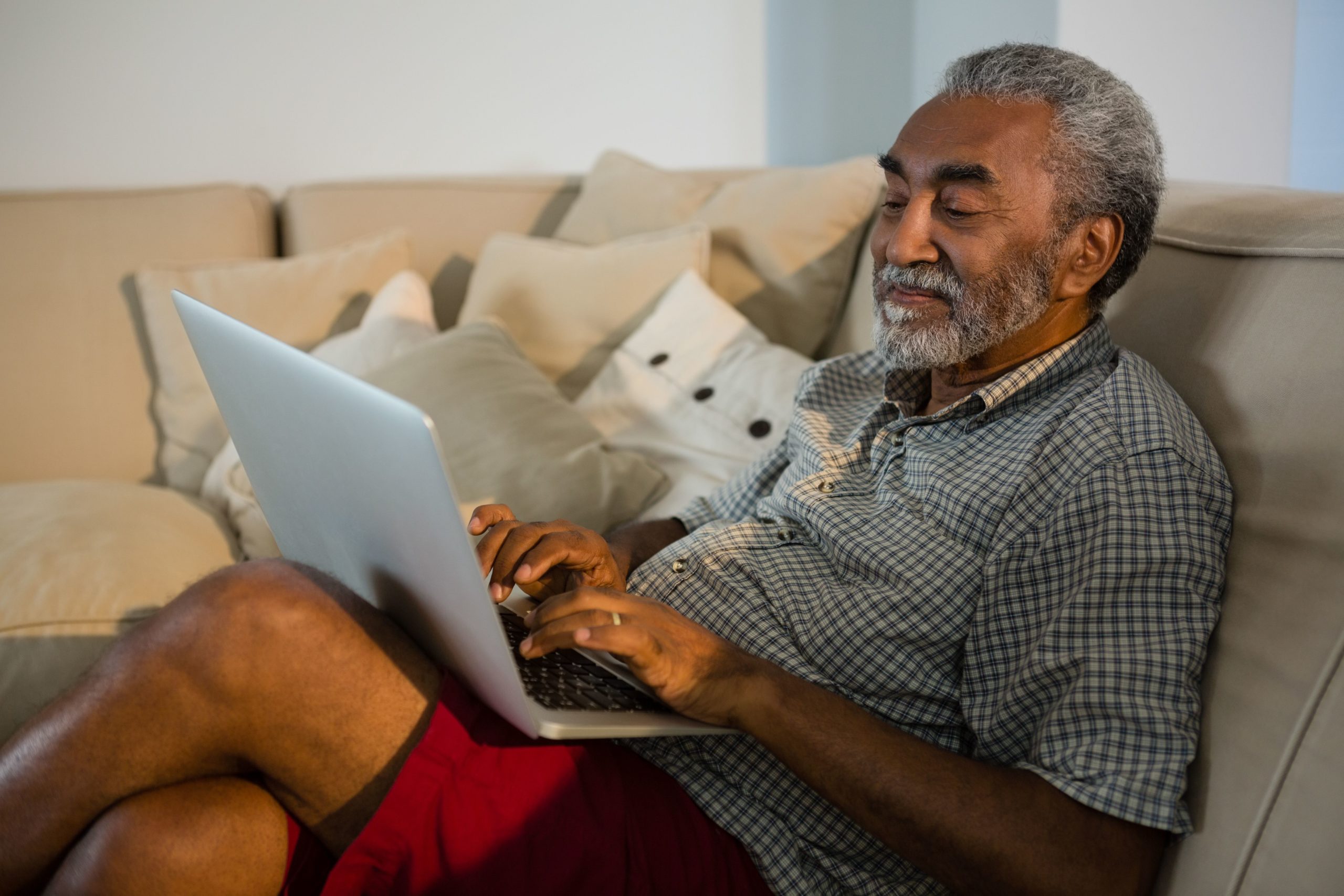 Senior sitting on couch with laptop